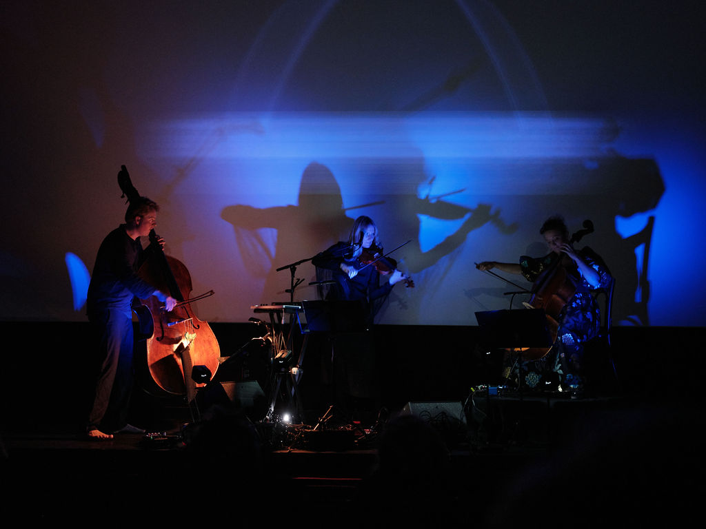 Ensemblet på scenen med blå live visuals